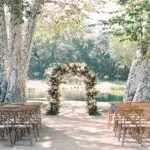 Monserate Winery's lakeside wedding venue in San Diego with a floral wedding arch standing between two giant sycamore trees.